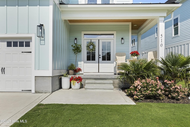 510 White Picket Way, Holly Ridge, NC 28445 - doorway to property with covered porch, a garage, board and batten siding, french doors, and a lawn
