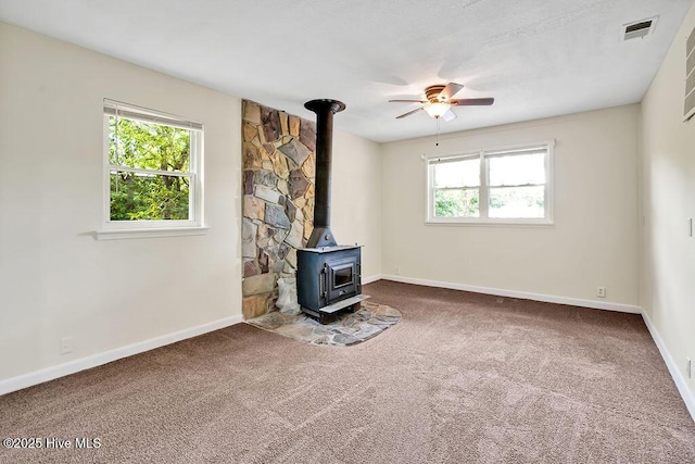 326 Spartan Rd, Wilmington, NC 28405 - unfurnished living room featuring a wood stove, ceiling fan, carpet, and baseboards