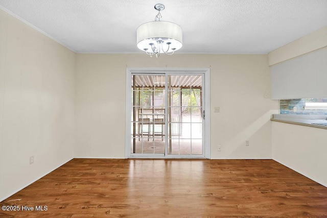 326 Spartan Rd, Wilmington, NC 28405 - unfurnished dining area with a chandelier, a textured ceiling, wood finished floors, and crown molding