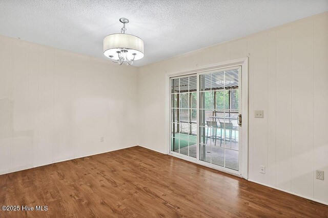 326 Spartan Rd, Wilmington, NC 28405 - unfurnished room featuring wood finished floors, a chandelier, and a textured ceiling