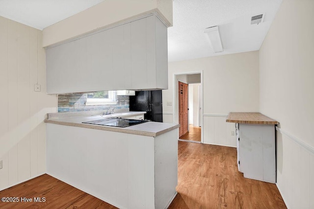 326 Spartan Rd, Wilmington, NC 28405 - kitchen with black appliances, light wood-type flooring, a peninsula, light countertops, and a decorative wall