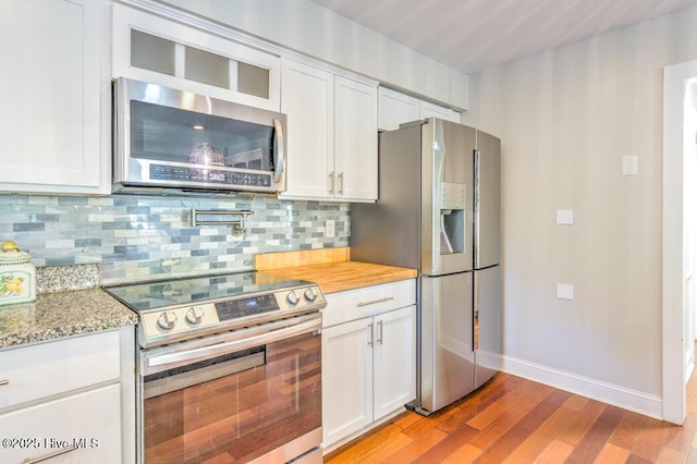 2428 Tram Rd, New Bern, NC 28562 - kitchen with appliances with stainless steel finishes, light wood-type flooring, white cabinets, and tasteful backsplash