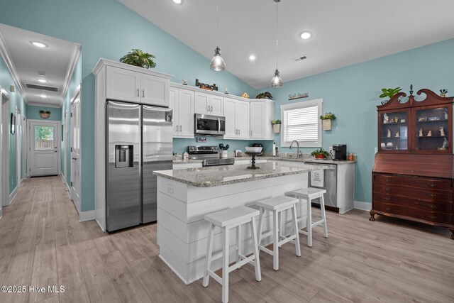 492 Jabbertown Rd, Southport, NC 28461 - kitchen with stainless steel appliances, a sink, lofted ceiling, a center island, and white cabinetry