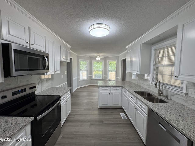 kitchen with stainless steel appliances, a sink, white cabinetry, a textured ceiling, and crown molding