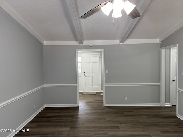 empty room with beam ceiling, dark wood-style floors, ceiling fan, and baseboards