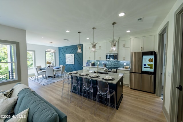 120 Fairview Rd, Leland, NC 28451 - kitchen with stainless steel appliances, a sink, white cabinets, a kitchen bar, and recessed lighting