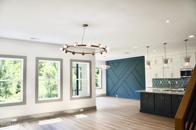 120 Fairview Rd, Leland, NC 28451 - kitchen featuring stainless steel microwave, white cabinets, a sink, light stone counters, and light wood-style floors