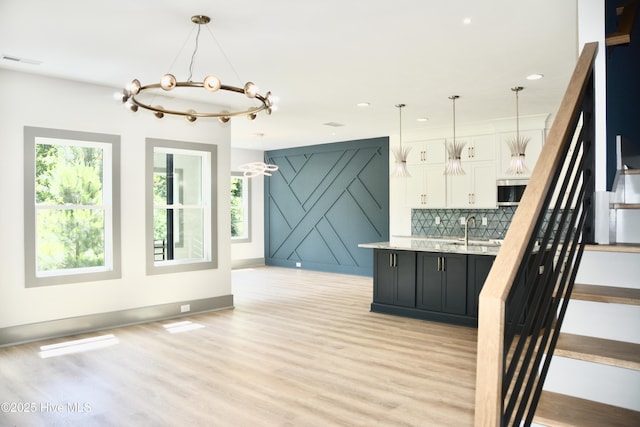120 Fairview Rd, Leland, NC 28451 - kitchen featuring light wood-style floors, white cabinets, open floor plan, a chandelier, and stainless steel microwave