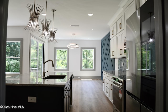 120 Fairview Rd, Leland, NC 28451 - kitchen featuring stainless steel appliances, a sink, light stone countertops, wood finished floors, and an island with sink