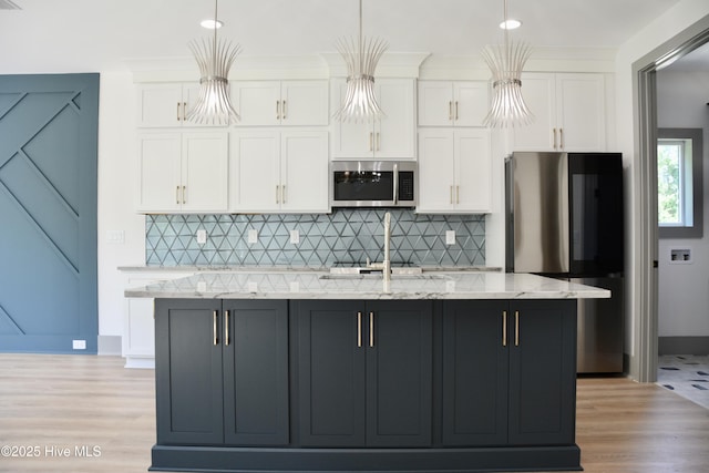 120 Fairview Rd, Leland, NC 28451 - kitchen featuring appliances with stainless steel finishes, white cabinetry, a kitchen island with sink, tasteful backsplash, and light wood-type flooring