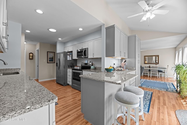 6008 Cassowary Ln, New Bern, NC 28560 - kitchen featuring stainless steel appliances, a sink, a peninsula, a breakfast bar area, and light wood-style floors