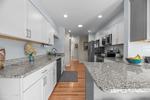 6008 Cassowary Ln, New Bern, NC 28560 - kitchen featuring stainless steel appliances, a sink, light wood-type flooring, light stone countertops, and white cabinetry