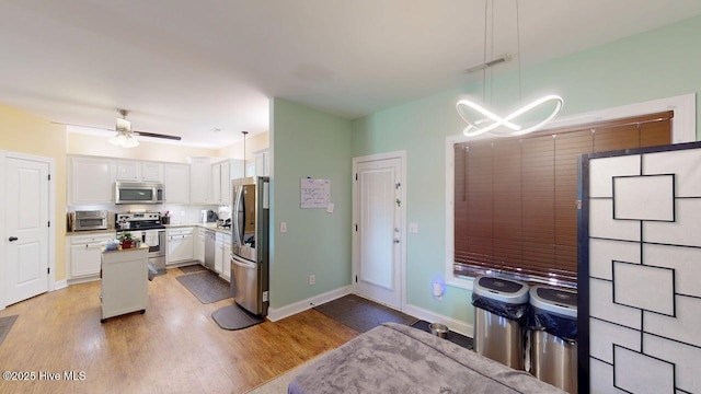 44 Nassau Ct, Clayton, NC 27520 - kitchen featuring appliances with stainless steel finishes, white cabinets, light wood-type flooring, a center island, and ceiling fan