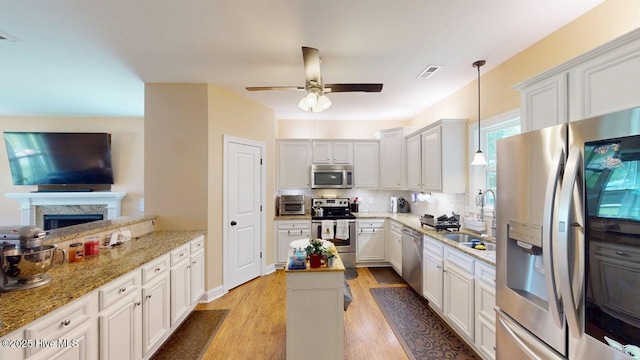 44 Nassau Ct, Clayton, NC 27520 - kitchen with stainless steel appliances, a sink, a ceiling fan, decorative backsplash, and light wood-style floors