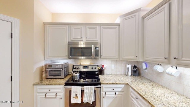 44 Nassau Ct, Clayton, NC 27520 - kitchen featuring appliances with stainless steel finishes, decorative backsplash, light stone counters, and white cabinetry