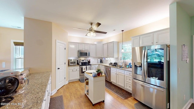 44 Nassau Ct, Clayton, NC 27520 - kitchen featuring appliances with stainless steel finishes, ceiling fan, light wood-type flooring, decorative backsplash, and a center island