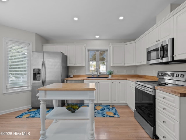 120 Buds Ln, Cedar Point, NC 28584 - kitchen featuring stainless steel appliances, butcher block counters, a sink, light wood-style flooring, and white cabinetry
