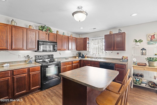 531 S NC Highway 343, Camden, NC 27921 - kitchen featuring black appliances, a sink, a kitchen bar, wood finished floors, and a kitchen island