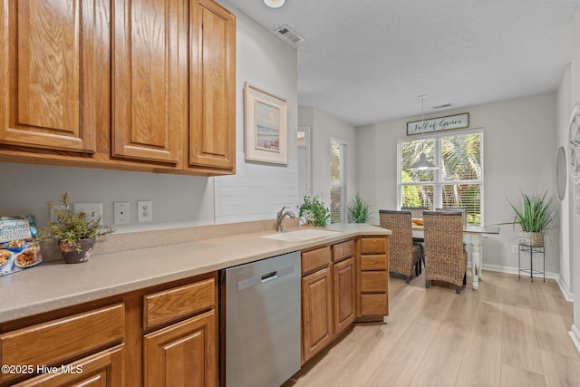 1424 Elgin St, Wilmington, NC 28409 - kitchen featuring stainless steel dishwasher, light wood-style flooring, brown cabinetry, and a textured ceiling