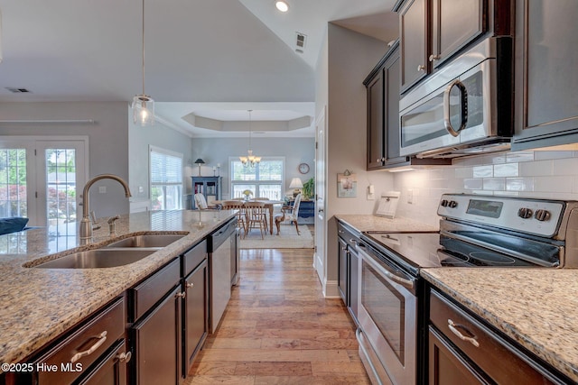 6122 Chancellorsville Dr, Wilmington, NC 28409 - kitchen with stainless steel appliances, a sink, a raised ceiling, dark brown cabinetry, and light wood finished floors
