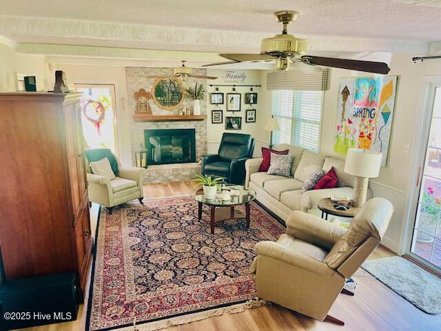 2008 Hardee Rd, Kinston, NC 28504 - living room featuring wood finished floors, a fireplace, ceiling fan, and a textured ceiling