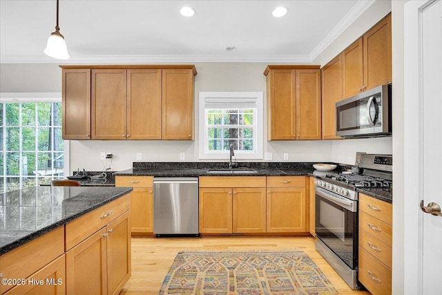 10196 Flint Ct SE, Leland, NC 28451 - kitchen featuring appliances with stainless steel finishes, a sink, light wood-type flooring, dark stone counters, and crown molding