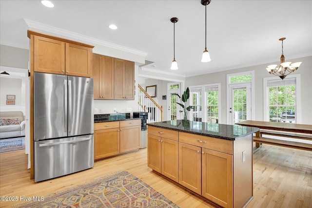 10196 Flint Ct SE, Leland, NC 28451 - kitchen with freestanding refrigerator, ornamental molding, light wood-style floors, dark stone countertops, and hanging light fixtures