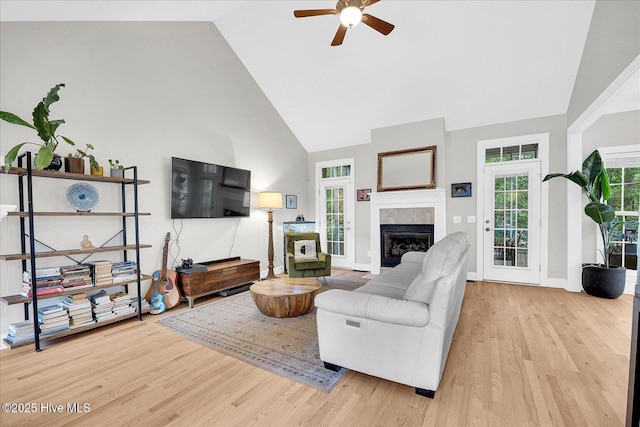 10196 Flint Ct SE, Leland, NC 28451 - living room featuring a glass covered fireplace, light wood-style flooring, ceiling fan, high vaulted ceiling, and baseboards