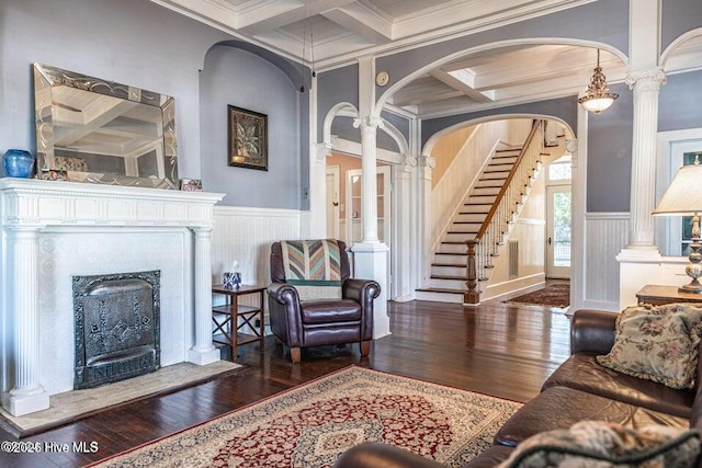 living area with coffered ceiling, crown molding, beam ceiling, hardwood / wood-style flooring, and a fireplace with raised hearth
