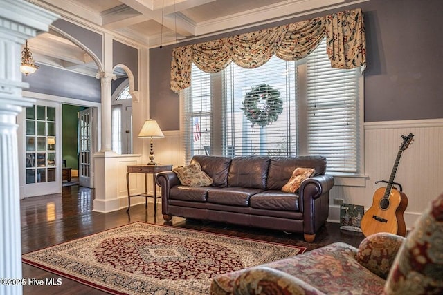 living room with ornamental molding, beamed ceiling, coffered ceiling, wainscoting, and wood finished floors