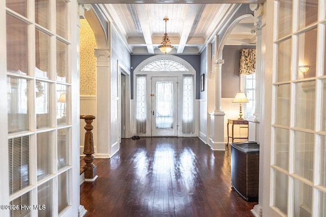 foyer entrance with arched walkways, a decorative wall, ornamental molding, wainscoting, and hardwood / wood-style flooring