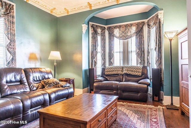 living area featuring arched walkways, ornamental molding, and wood finished floors