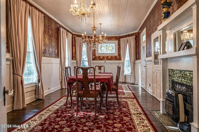 dining space featuring a chandelier, ornamental molding, dark wood-style flooring, wainscoting, and a decorative wall