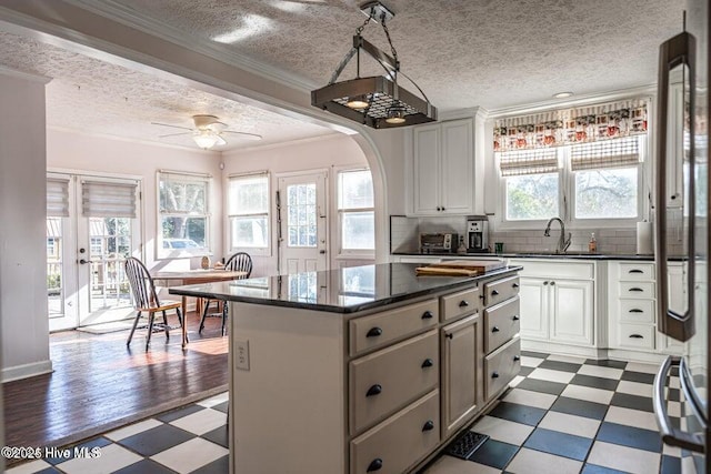 kitchen with dark flooring, a textured ceiling, a sink, a center island, and backsplash