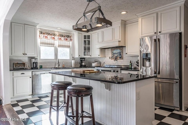kitchen featuring appliances with stainless steel finishes, light floors, a textured ceiling, glass insert cabinets, and a kitchen bar