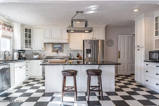 kitchen featuring light floors, stainless steel appliances, dark countertops, a center island, and a textured ceiling