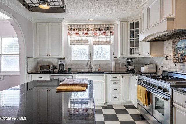 kitchen with range with two ovens, a sink, tile patterned floors, arched walkways, and dark countertops