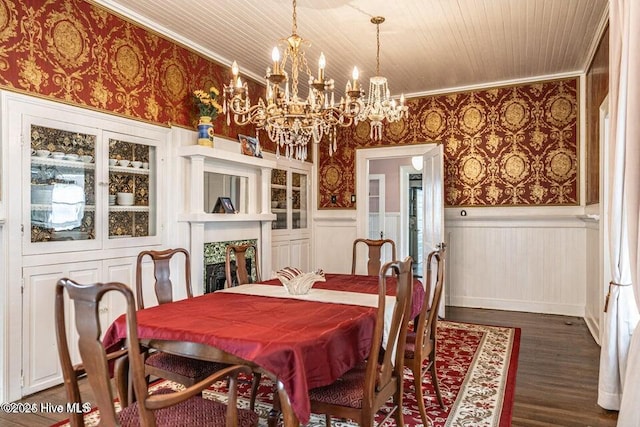 dining space featuring wainscoting, ornamental molding, a chandelier, wallpapered walls, and dark wood-style floors