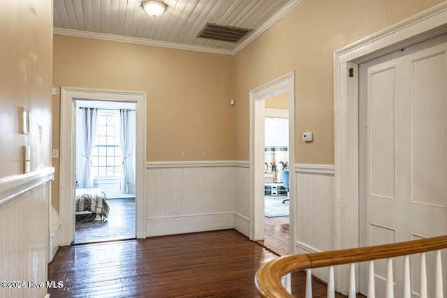 hallway with wood finished floors, wainscoting, and ornamental molding