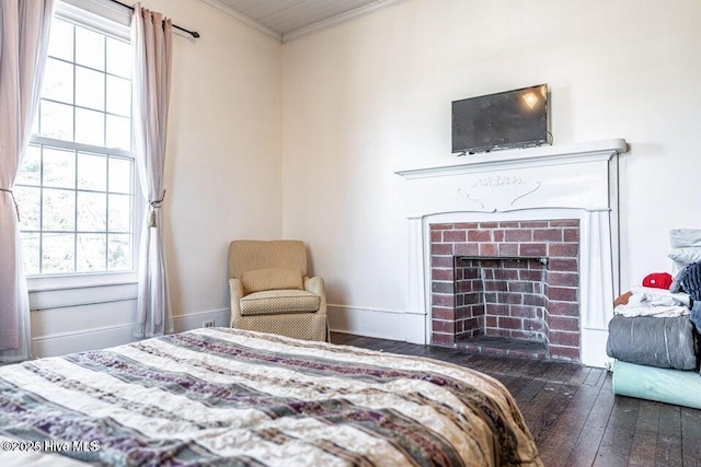 bedroom featuring ornamental molding, multiple windows, wood-type flooring, and a brick fireplace