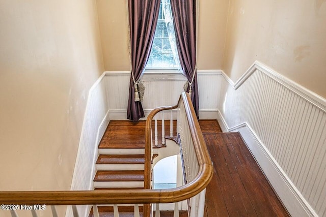 stairway with wainscoting and wood finished floors