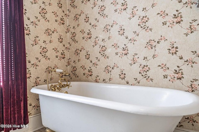 full bath with wallpapered walls and a freestanding tub