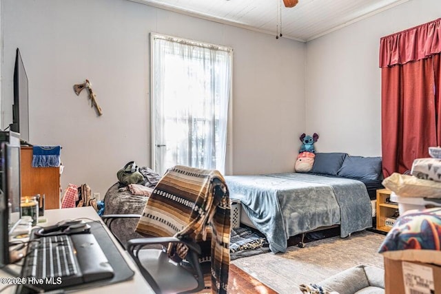 bedroom with ornamental molding and wood finished floors
