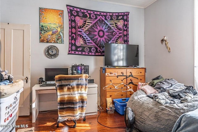bedroom featuring ornamental molding, wood finished floors, and a desk