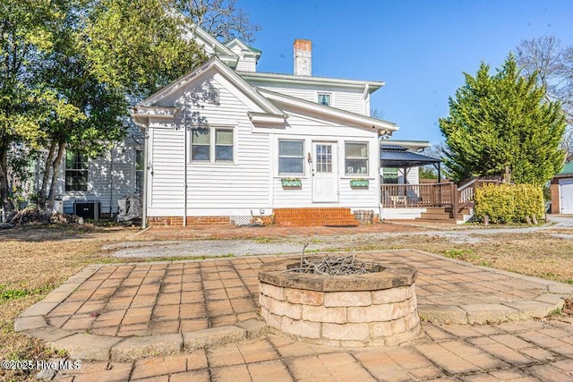 back of property with a patio, a chimney, an outdoor fire pit, a deck, and a gazebo