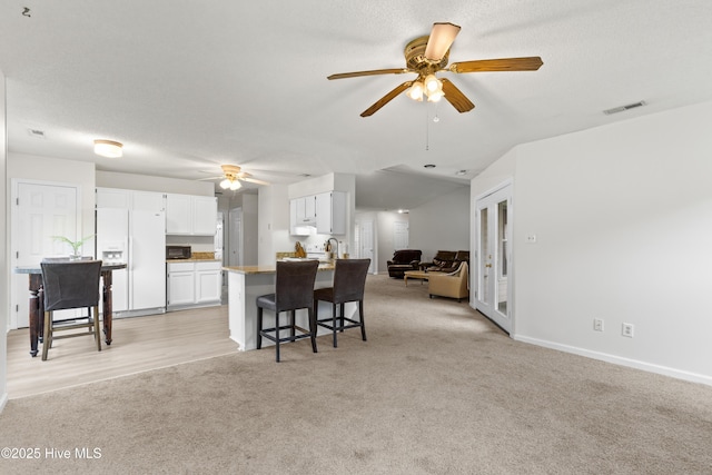 510 Greenfield Pl, Sneads Ferry, NC 28460 - kitchen featuring white fridge with ice dispenser, ceiling fan, white cabinetry, open floor plan, and light colored carpet