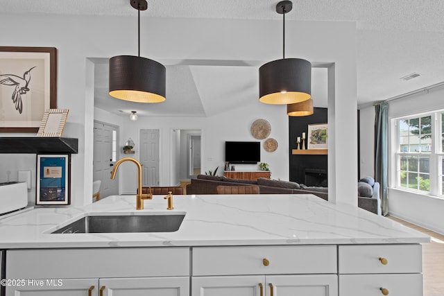 415 Point View Ct, Wilmington, NC 28411 - kitchen with a sink, a textured ceiling, white cabinets, open floor plan, and light stone countertops