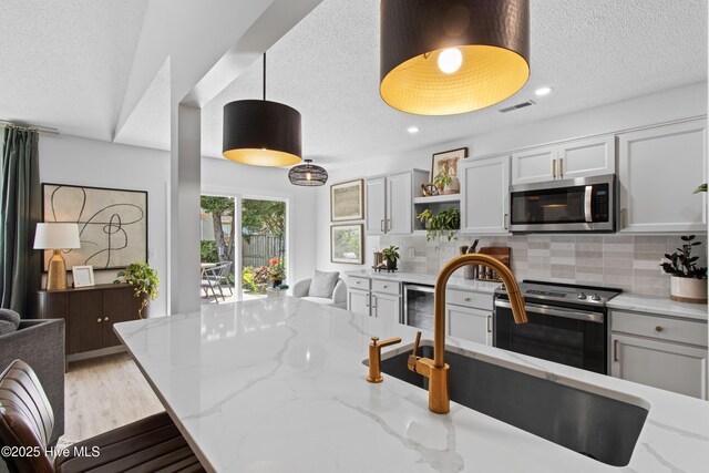 415 Point View Ct, Wilmington, NC 28411 - kitchen with appliances with stainless steel finishes, a textured ceiling, a sink, open shelves, and tasteful backsplash