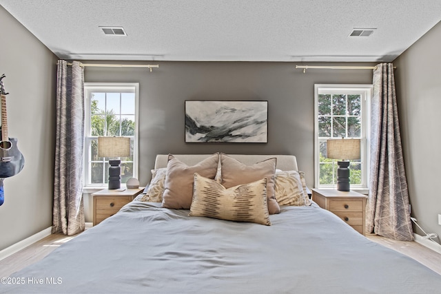 415 Point View Ct, Wilmington, NC 28411 - bedroom with wood finished floors, baseboards, a textured ceiling, and multiple windows
