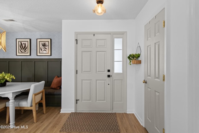 415 Point View Ct, Wilmington, NC 28411 - entryway featuring light wood-type flooring, a textured ceiling, and wainscoting